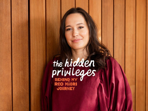 Māori woman wearing a maroon shirt with text about hidden privileges in my Reo Māori journey against a wooden background