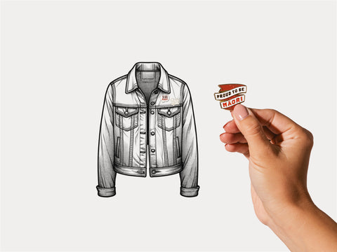 A hand holding a pin with the text "Proud to be Māori" in front of an illustration of a denim jacket with a similar pin already attached to the lapel.