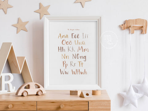 Framed Māori alphabet print on a dresser with wooden decor and star hangings.