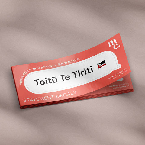 Stack of 'Toitū Te Tiriti' decal vinyl stickers on textured background and diffused light and shadows featuring Māori tino rangatiratanga flag