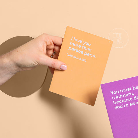 Hand holding a bright card with the text 'I love you more than parāoa parai.' on a pastel yellow background