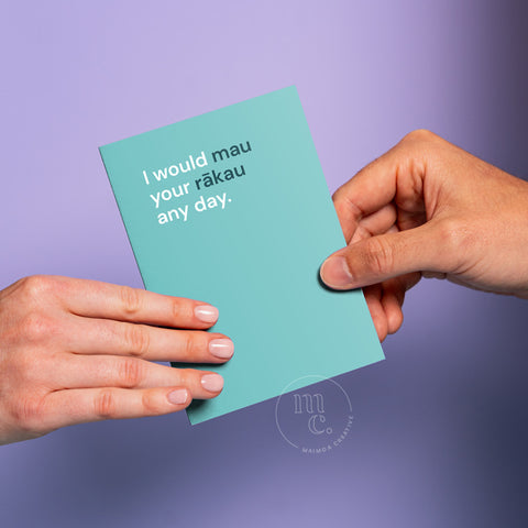 Hand passing an R18 greeting card with the text 'I would mau your rākau any day.' on a pastel purple background