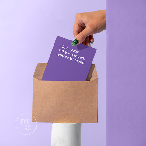 R18 card being pulled by a hand from a kraft envelope on a plinth with the text 'I love your teke - I mean, you're tu meke' against a pastel purple background.
