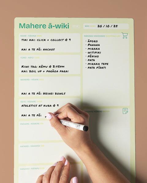 Hand writing on a large green A3 weekly magnetic planner with a brown background