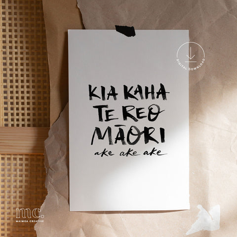 White paper with black text "Kia kaha te reo Māori ake ake ake" on a textured brown background