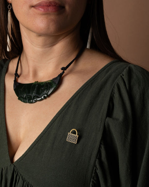 Woman wearing a dark green dress with a gold kete basket brooch