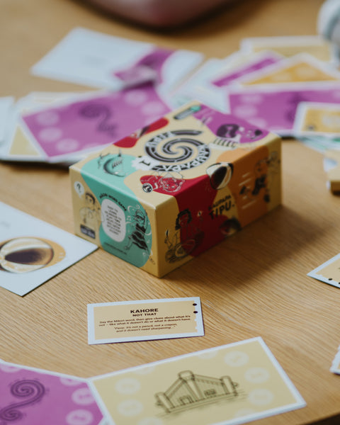 Colourful māori card game box with playing cards on a wooden surface