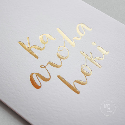 Closeup of a premium reo Māori greeting card with 'Ka aroha hoki' in gold foil lettering