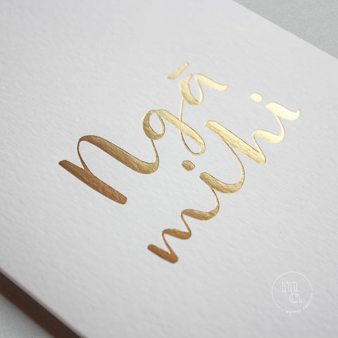 Closeup of a premium reo Māori greeting card with 'Ngā Mihi' in gold foil lettering
