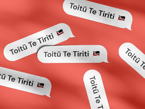 Multiple "Toitū Te Tiriti" vinyl decals on a bright red textured background, showcasing elegant design with the Māori tino rangatiratanga flag