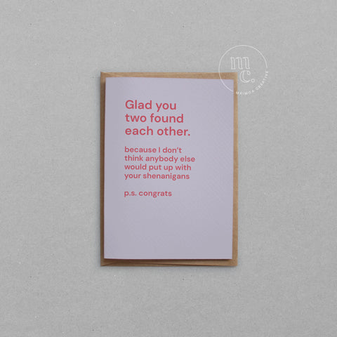 Greeting card with text 'Glad you two found each other because I don’t think anybody else would put up with your shenanigans' on a pastel purple background, placed on a light surface