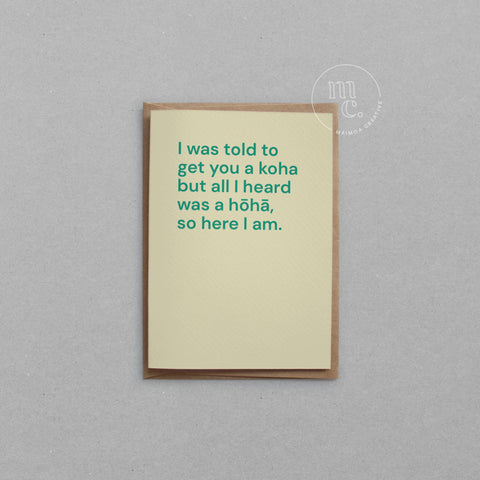 Greeting card with text 'I was told to get you a koha but all I heard was a hōhā, so here I am.' on a light yellow background, placed on a light surface