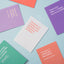 Assorted colourful cheeky greeting cards with playful Māori-themed messages spread on a pastel blue background.