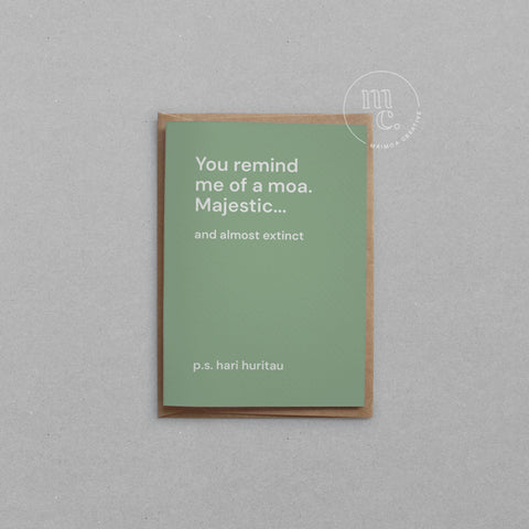 Greeting card with text 'You remind me of a moa. Majestic...and almost extinct' on a earthy green background, placed on a light surface