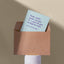 Cheeky card peeping from a kraft envelope on a plinth with the text 'Yeah, yeah, yeah, we get it — you’ve got a degree now. You're still an egg,' against a beige background.

