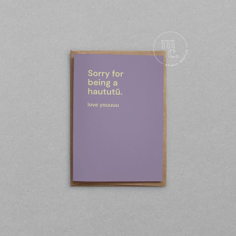 Greeting card with text 'Sorry for being a haututū. love youuuu' on a pastel purple background, placed on a light surface