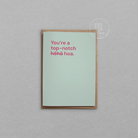 Greeting card with text 'You're a top notch hōhā/hoa' on a light mint green background, placed on a light surface