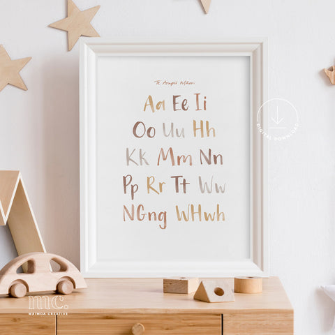 Earthy brown Māori alphabet poster in alphabetical order framed on a wooden nursery dresser, featuring the letters vowels and digraphs