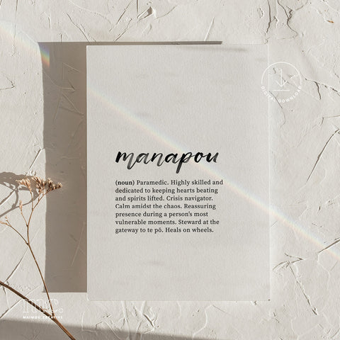 Art print of 'manapou' definition casting a rainbow shadow, placed on a textured surface with dried flowers