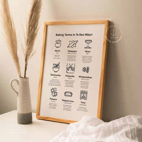 A stylish framed print displaying 'Baking Terms in Te Reo Māori' alongside a modern vase and dried grass, set in a cozy home environment.