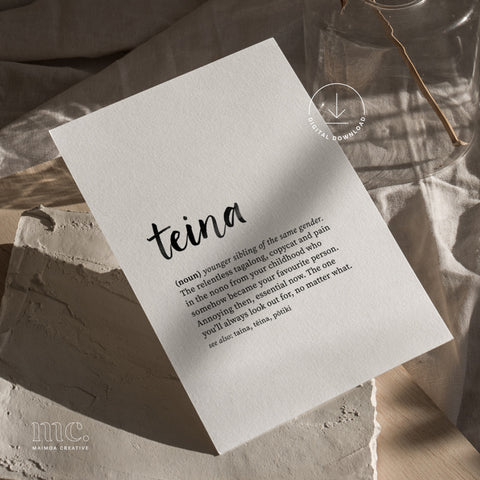 Flat-lay of teina definition print on textured paper with warm light and neutral styling. Reo Māori family term wall art, digital download print.