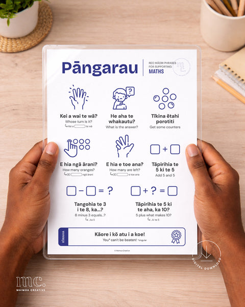Person holding a 'Pāngarau' reo Māori maths reference sheet on a wooden surface