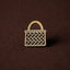 Gold woven kete basket pin on a brown background