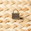 Bronze kete basket pin on a woven harakeke background