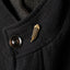Gold huia feather pin on a dark coat collar with a button