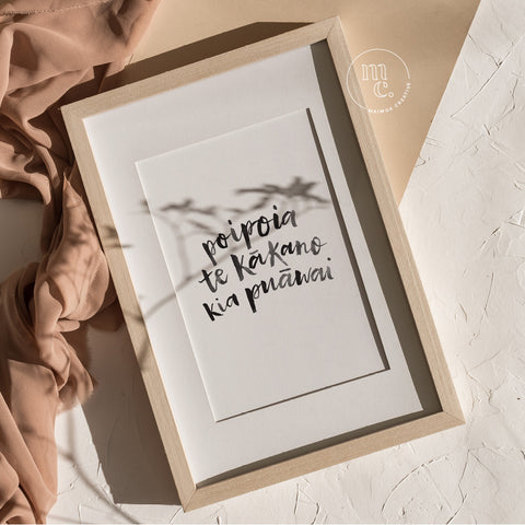 Framed A4 Māori art print with hand-lettered text “Poipoia te kākano kia puāwai” styled in soft natural light.