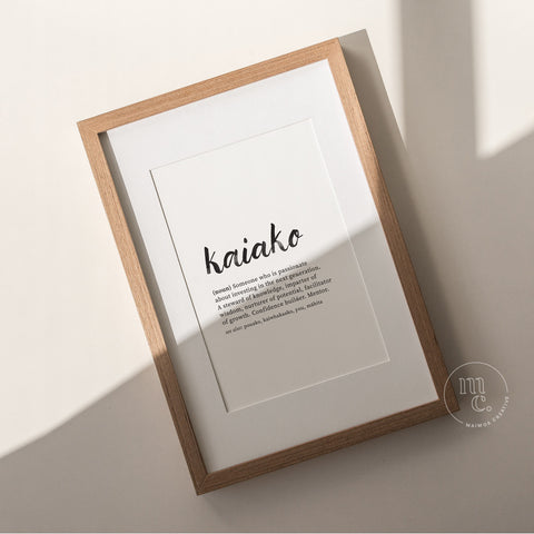 Framed Kaiako Māori definition art print photographed on an angle in soft natural light on a neutral background.