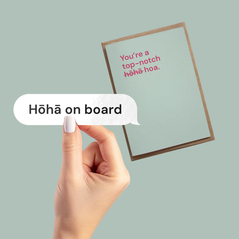 Hand holding a vinyl decal with "Hōhā on board" in a speech bubble design, over a greeting card with "You're a top-notch hōhā-hoa" message.