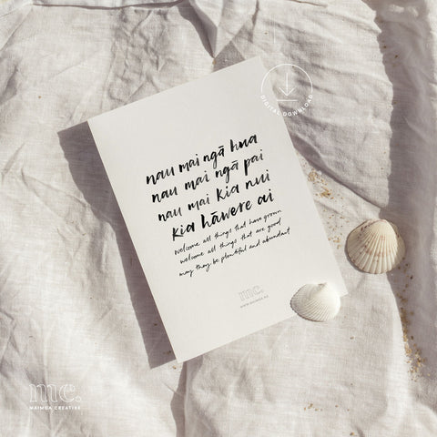 Māori blessing print "Nau mai ngā hua" on a linen background, embellished with delicate seashells.