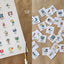 Sheet of reo Māori routine cards with illustrations being trimmed into small white squares
