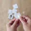 Hands holding a small white routine card adding a velcro dot to it