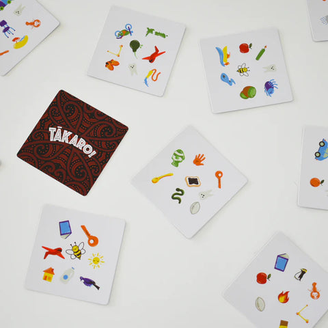 Colourful Tākaro card game cards with various symbols on a white surface